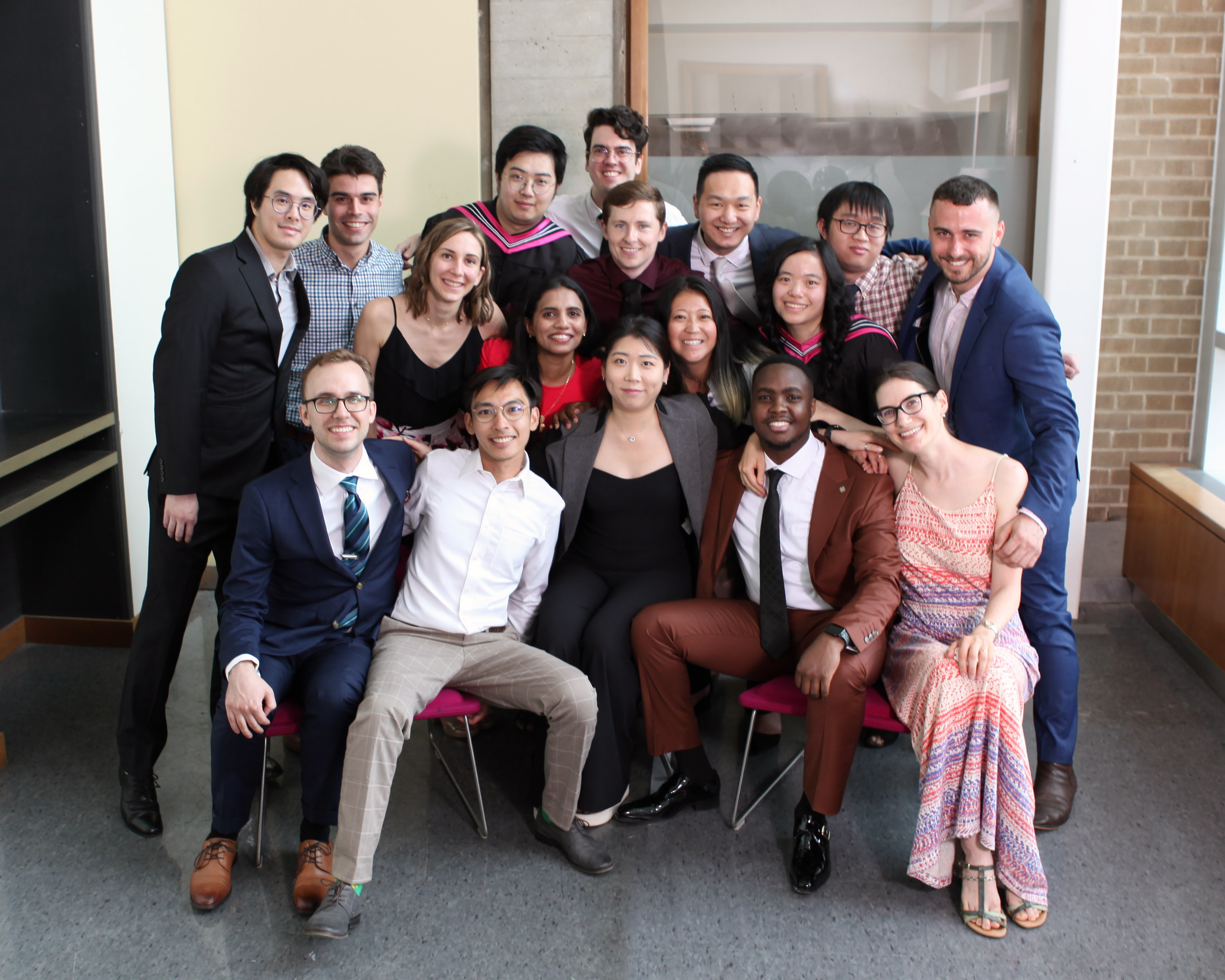 A group of 17 well-dressed adults clusters together, smiling at the camera.