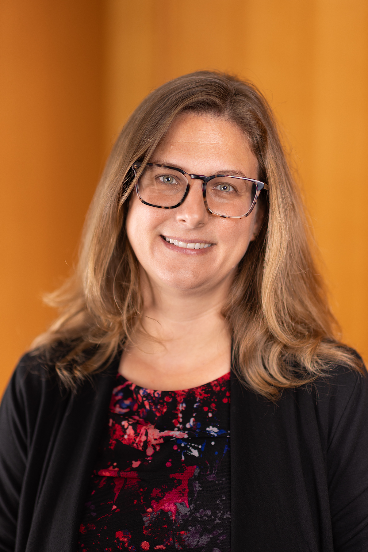 Head shot of Professor Jess D'eon, a white woman with long golden-brown hair and glasses.