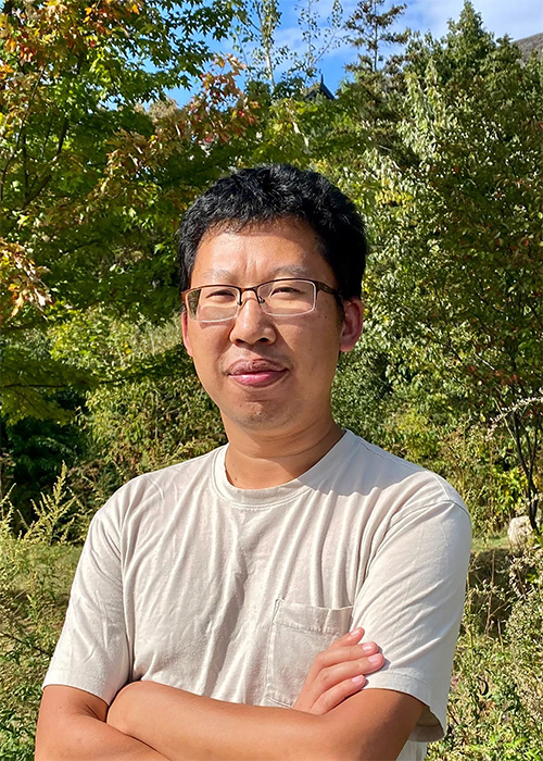 Outdoor shot of Professor Hui Peng in front of some trees.