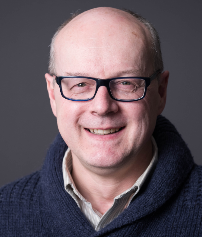 Professor Gilbert Walker, a white man with glasses in a brown sweater.