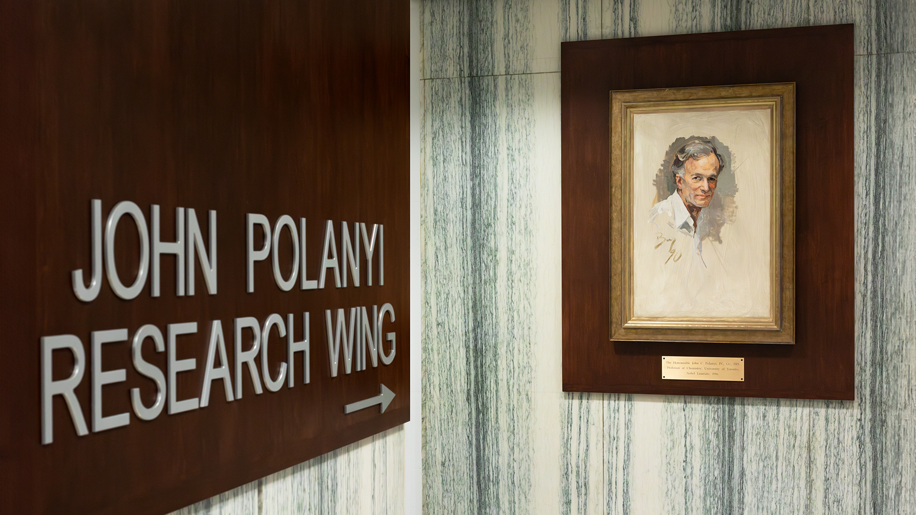 Painting of a white man next to the sign for the John Polanyi Research Wing