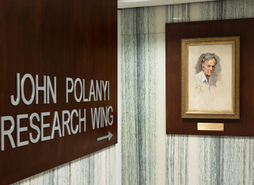 Painting of a white man next to the sign for the John Polanyi Research Wing