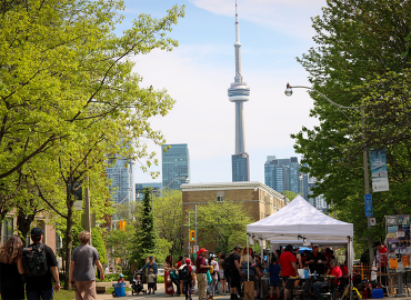People gather on the UofT front campus with the CN Tower in the background.