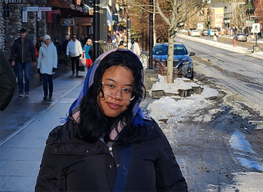 Chemistry student Jamieleen Pingol stands in winter gear in front of a road terminating in a mountain.